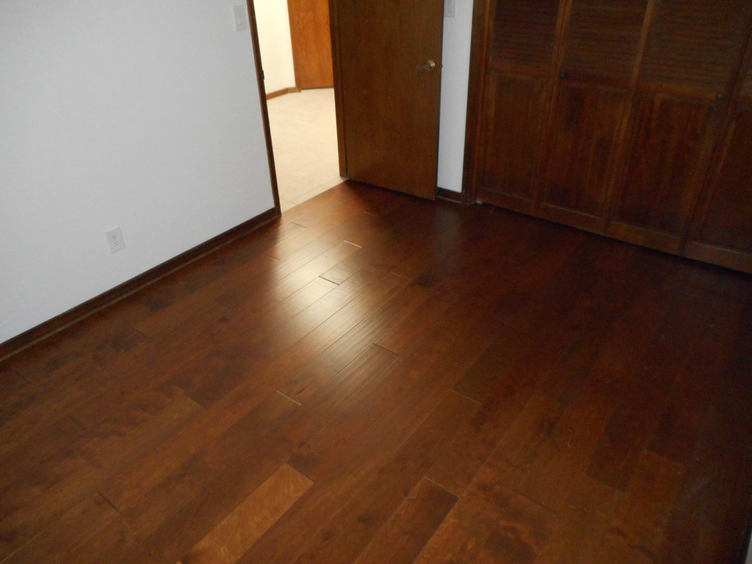 The same bedroom finished in wide plank hardwood running through the doorway