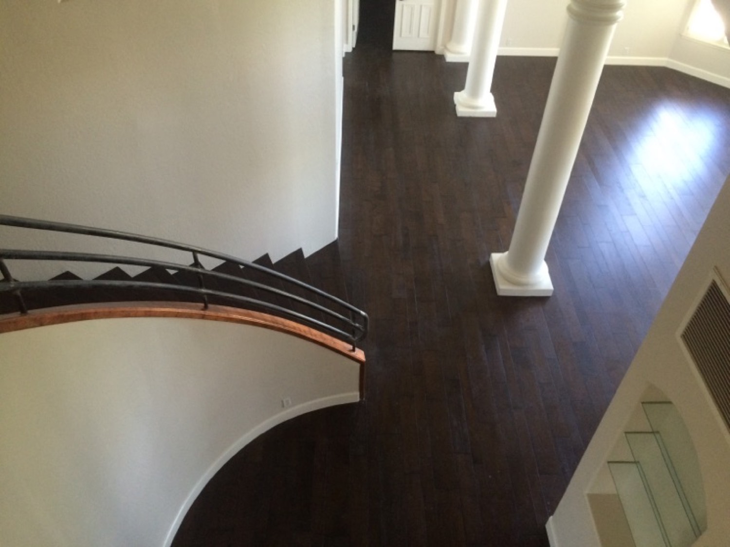 The same curved staircase finished in dark hardwood, treads and risers cut to the radius