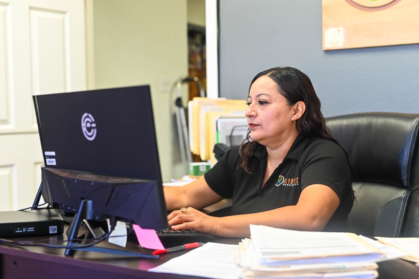 Olympic team member working at the showroom desk with paperwork and a computer