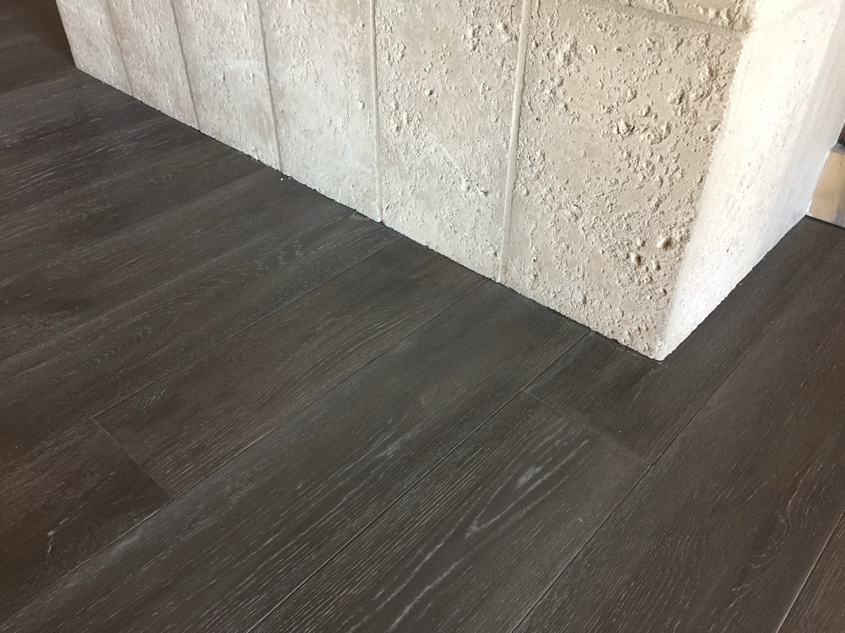Dark plank flooring meeting a travertine column