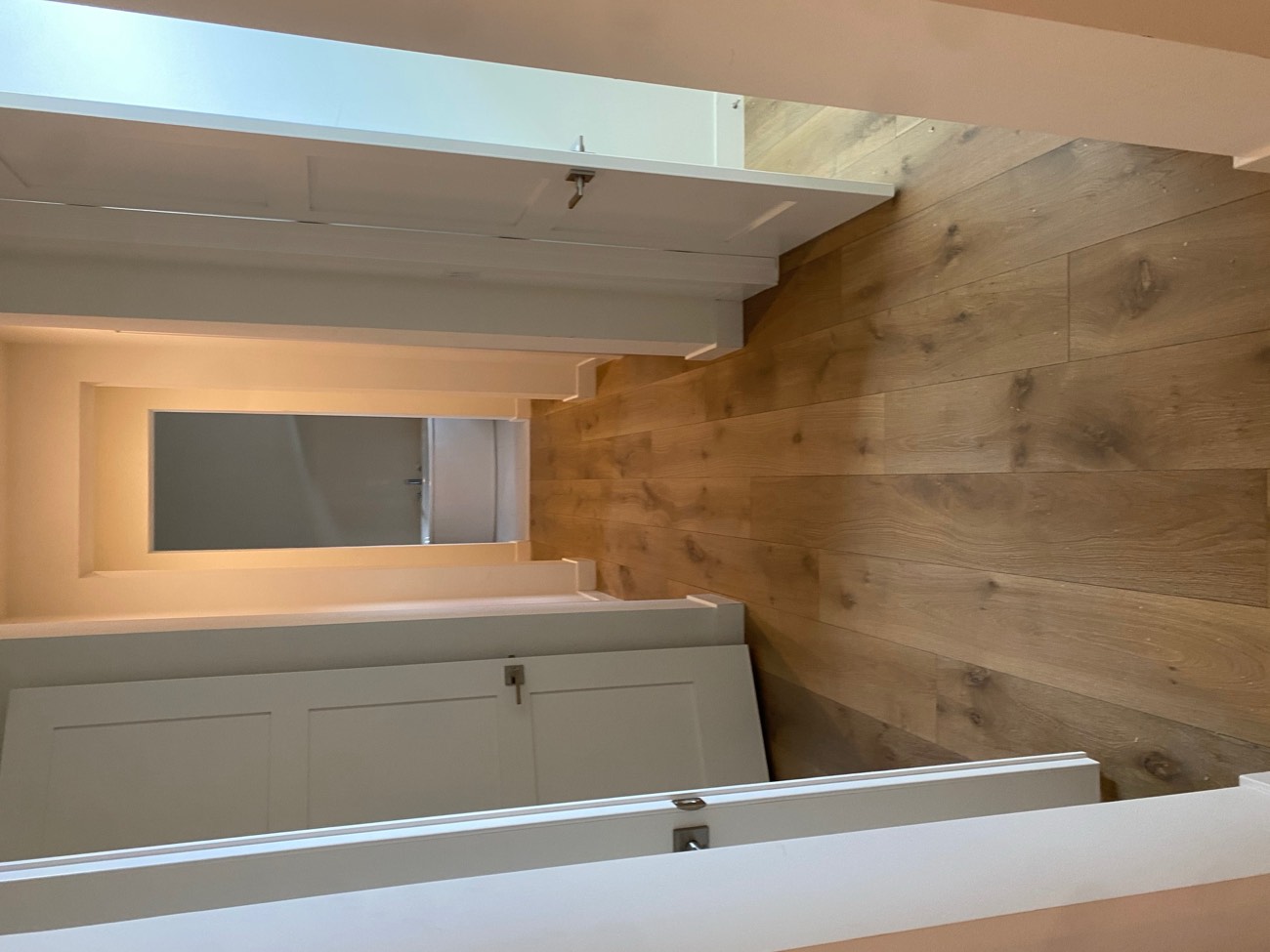 Finished hardwood hallway running through several doorways without a threshold strip