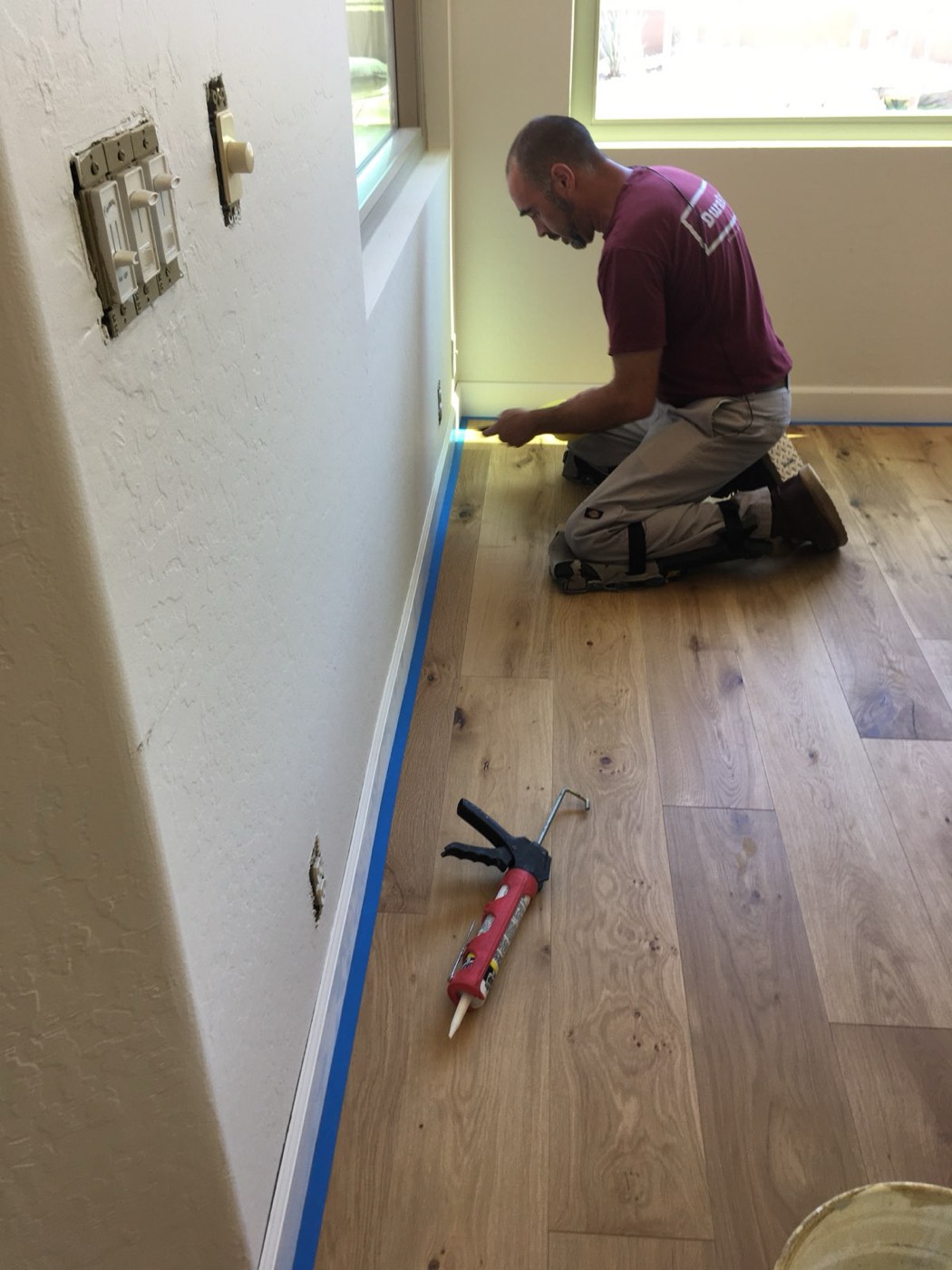 Installer fitting trim against a finished hardwood floor