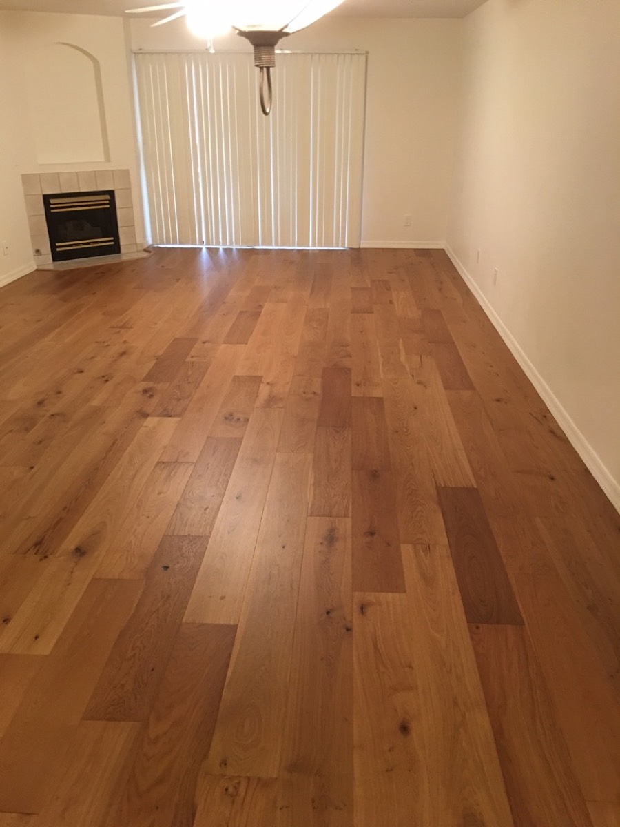 Refinished oak floor in an empty Phoenix living room with a fireplace