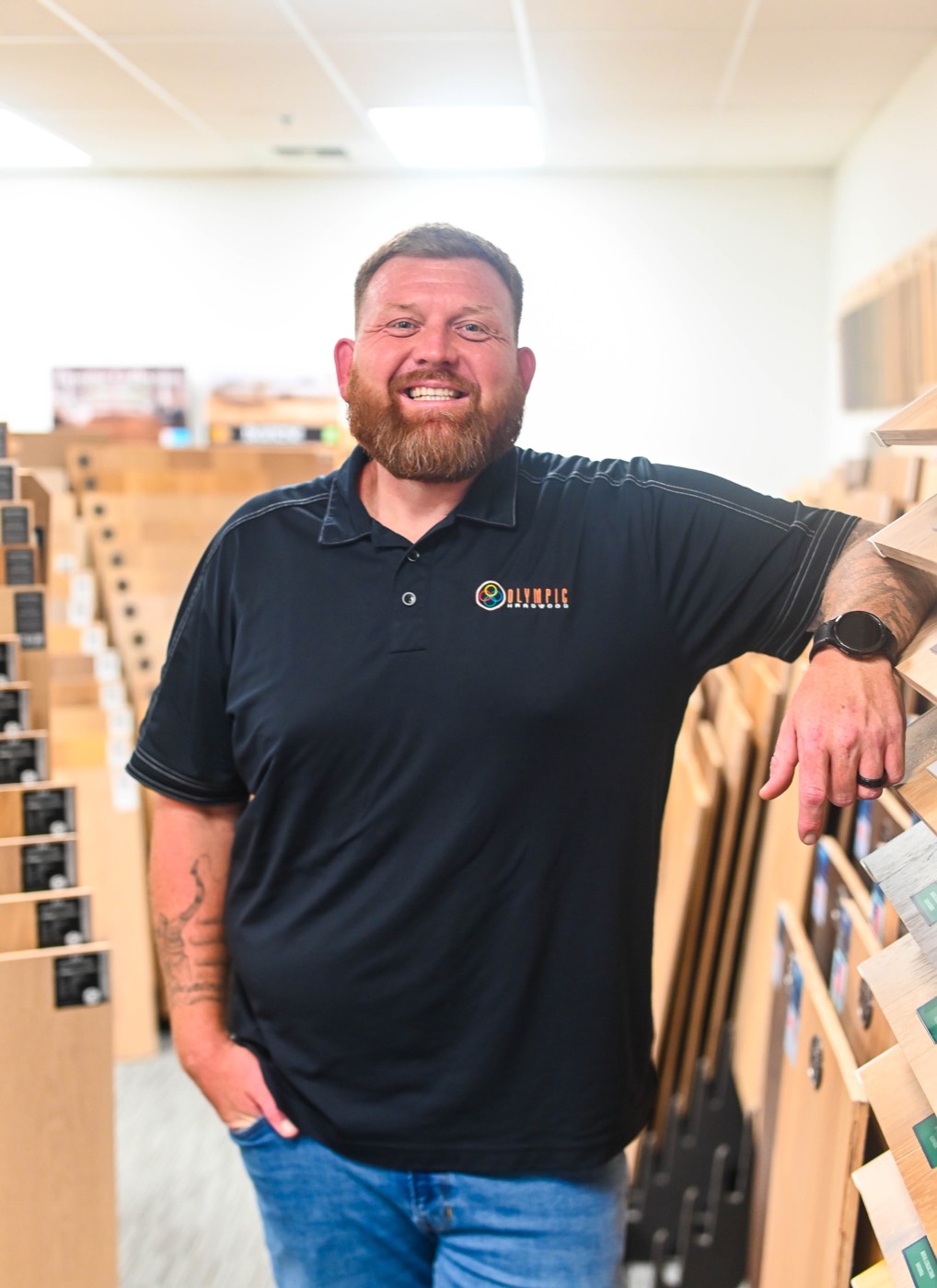 Member of the Olympic team beside a rack of hardwood samples