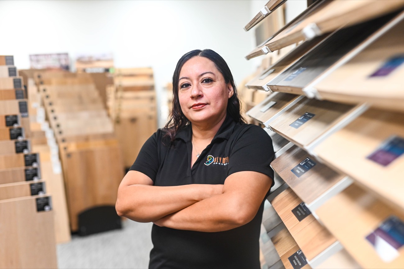 Member of the Olympic team standing among the sample racks in the Phoenix flooring store
