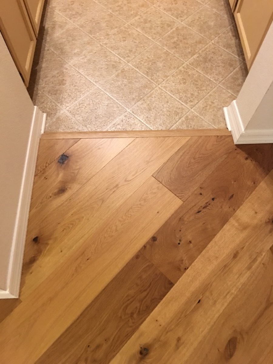 Threshold where hardwood meets remaining tile, showing the height difference